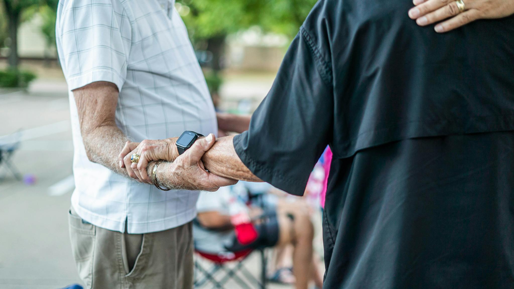 Two senior adults holding hands symbolizing friendship and connection.